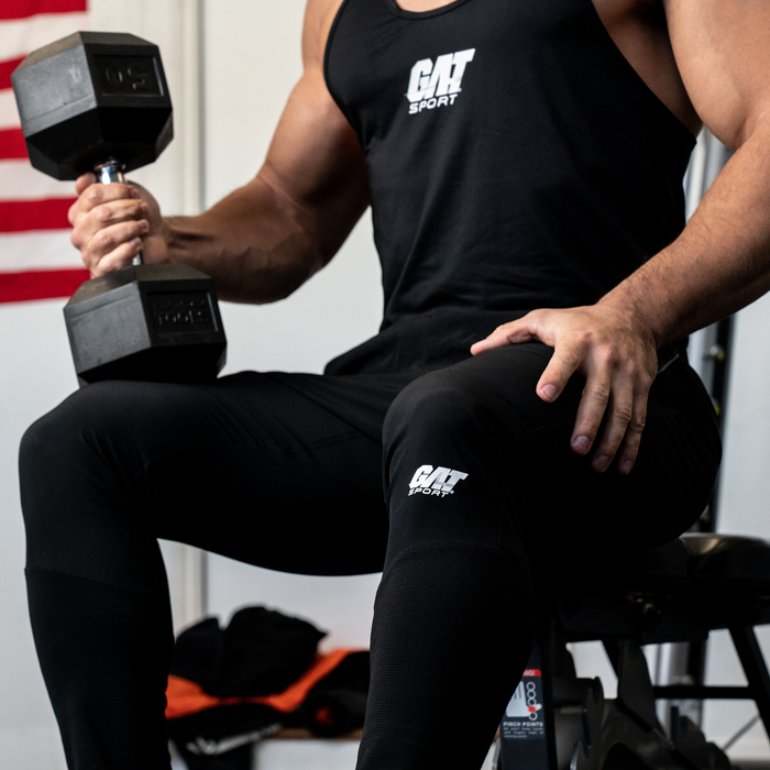 Photo of a male fitness influencer working out in the gym with a GAT Tan top and Sport pants